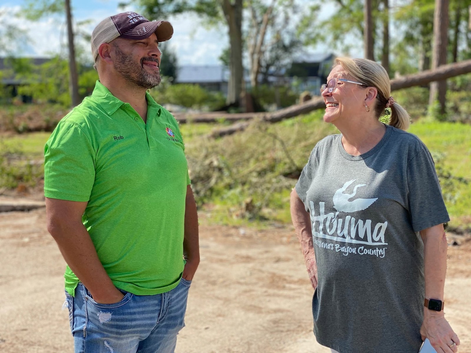 Rob Gaudet in a Cajun Navy shirt, laughing with a volunteer at a storm cleanup site.
